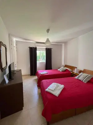 a room with two beds with red sheets and a window at Algarvila in Vilamoura