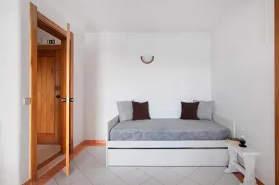 a white bedroom with a bed and a table at Apartamento Varandas do Mar, Praia dos Pescadores, Albufeira in Albufeira