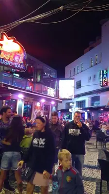 a group of people walking down a street at night at Peneco II in Albufeira