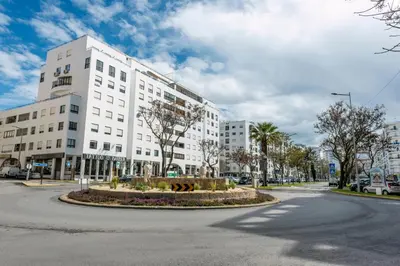 a large white building with a roundabout in the street at Blue Boat in Quarteira