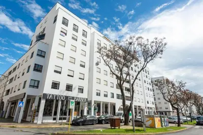 a white building with cars parked in front of it at Blue Boat in Quarteira