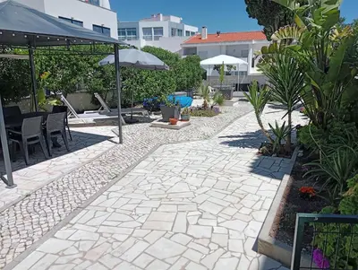 a patio with a stone walkway with chairs and umbrellas at Little Wonder Apartment in Albufeira