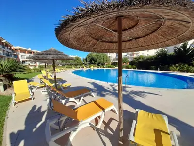 a group of chairs and umbrellas next to a swimming pool at Blue House Corcovada in Albufeira
