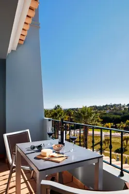 a table with wine glasses on a balcony with a view at Ancão Gardens in Quinta do Lago