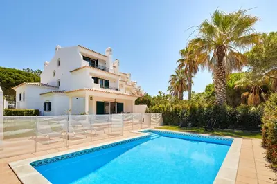 a villa with a swimming pool in front of a house at Ancão Gardens in Quinta do Lago