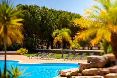 a group of chairs sitting next to a swimming pool at Ancão Gardens in Quinta do Lago