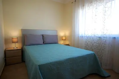 a bedroom with a bed with a blue bedspread and a window at Apartamento Edificio Ibérico - Albufeira downtown in Albufeira