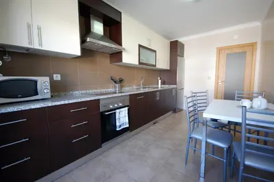 a kitchen with brown cabinets and a table and a microwave at Apartamento Edificio Ibérico - Albufeira downtown in Albufeira