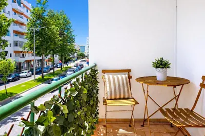 a balcony with a table and chairs and a street at Avenue Apartment in Quarteira