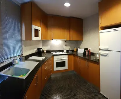a kitchen with wooden cabinets and a white refrigerator at Albufeira Marina Villa 27 in Albufeira
