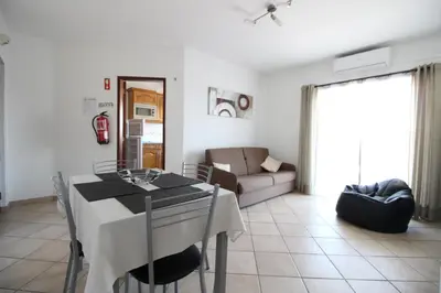 a kitchen and living room with a table and a couch at Dinita Apartamento nº4 in Albufeira