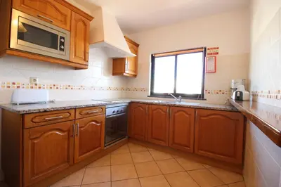 a kitchen with wooden cabinets and a sink and a window at Dinita Apartamento nº4 in Albufeira