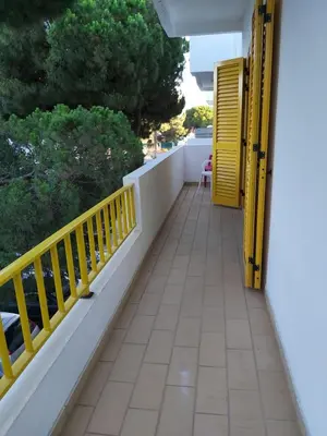 a balcony with a yellow railing and trees at GelbBlau Falésia in Albufeira