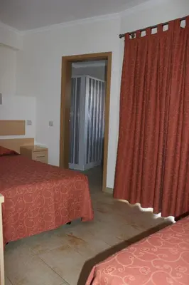 a hotel room with two beds and a red curtain at Dom Fernando II in Loulé