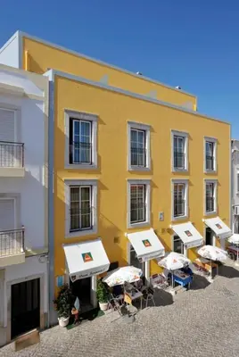 a yellow building with tables and chairs in front of it at Dom Fernando II in Loulé