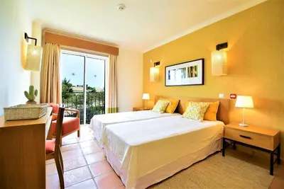 a bedroom with a large white bed and a window at T3 Vila Sol Village in Quarteira