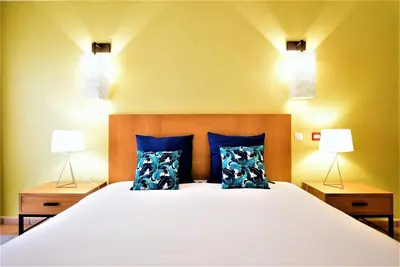 a bedroom with a bed with blue pillows and two lights at T3 Vila Sol Village in Quarteira