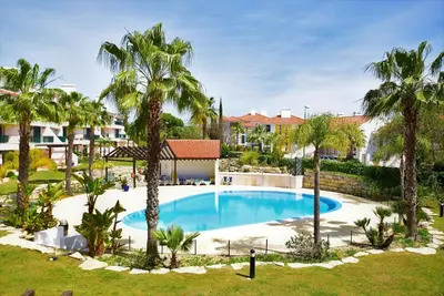 an image of a swimming pool with palm trees at T3 Vila Sol Village in Quarteira