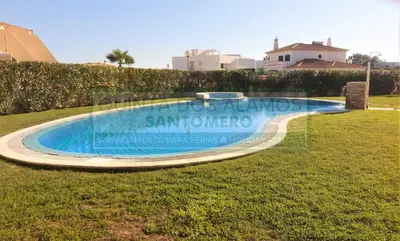 a swimming pool in the middle of a grass field at Moradia Townhouse Vila Rosal 2 in Albufeira