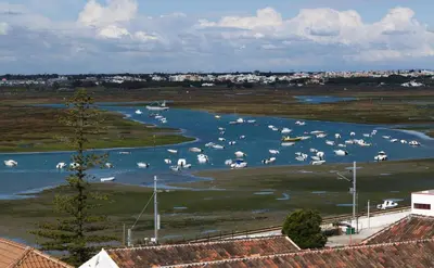 a group of boats floating in a river at 1977 in Faro