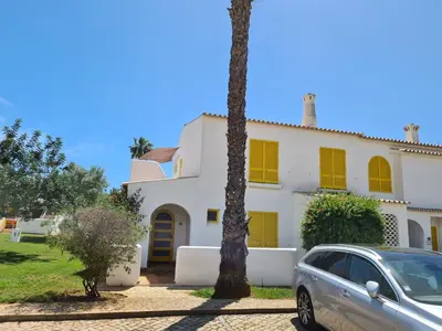 a car parked in front of a house with yellow shutters at Aldeia do Golf - Vila I4 in Vilamoura