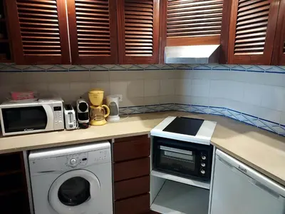 a kitchen with a microwave and a washing machine at Bellavista Tenis Clube A4 T1 - Albufeira INN in Albufeira