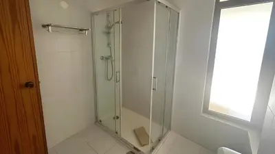 a glass shower in a bathroom with a window at Albufeira Cerro Branco (23) in Albufeira