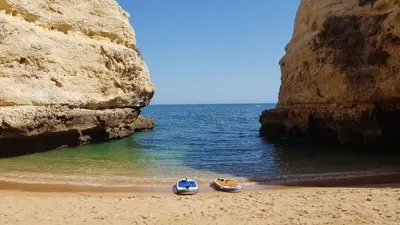 two boats sitting on a beach next to the ocean at Albufeira sea view (52) in Albufeira