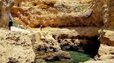 a person standing on a cliff next to a body of water at Albufeira sea view (52) in Albufeira