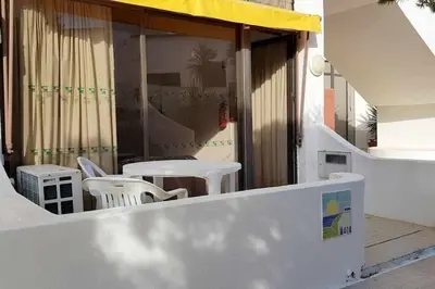 a patio with white chairs and tables on a building at Albufeira, Cerro Branco (42) in Albufeira