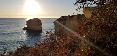 a sunset over the ocean with a rock in the water at Albufeira, Sea Balcony (11) in Albufeira