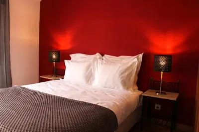 a bedroom with a red wall and a bed with white pillows at Alameda Garden in Faro