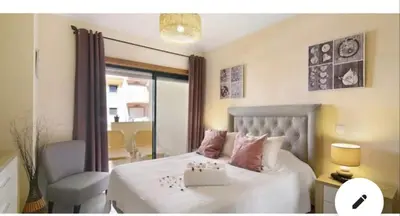 a bedroom with a white bed with a chair and a window at Appartement Villamoura in Vilamoura