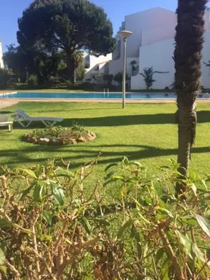 a park with a bench and a tree in the grass at Apartamento 24 SOL in Vilamoura