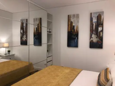 a bedroom with two beds and paintings on the wall at Apartamento 24 SOL in Vilamoura
