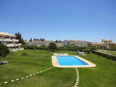 a large yard with a swimming pool in the grass at Citymar by FHR T2 com piscina in Vilamoura