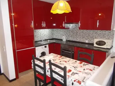 a kitchen with red cabinets and a table with chairs at Bellavista Studio in Albufeira