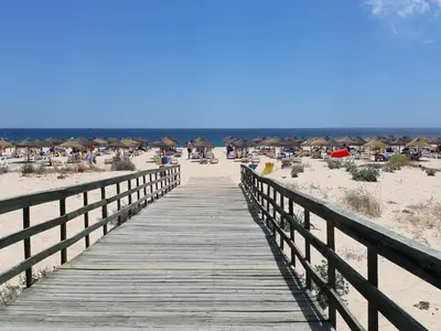 a wooden boardwalk leading to a beach with huts at Sol Nascente- Piscina, Wifi, Familiar in Vilamoura