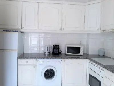 a white kitchen with a washer and a microwave at SATÉLITE AC&Garagem in Quarteira