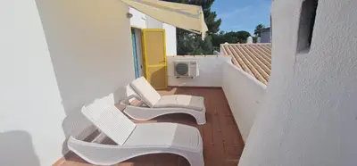 a balcony with two white chairs and a yellow door at V2 Aldeia Do Golf- Piscina, Familiar, Aconchegante in Vilamoura