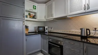 a kitchen with white cabinets and a microwave at 3 Bed Holiday Home Lakeside Village Quinta Do Lago in Faro