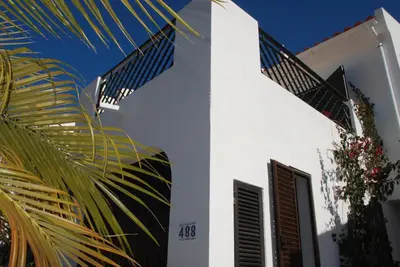 a white house with a palm tree in front of it at 3 Bed Holiday Home Lakeside Village Quinta Do Lago in Faro
