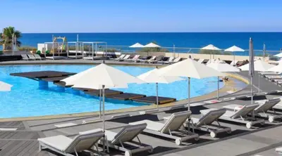 a swimming pool with chairs and umbrellas and the ocean at Beach Villa Vale do Lobo in Vale do Lobo