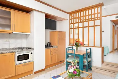 a kitchen with wooden cabinets and a table with chairs at Muthu Oura Praia Hotel in Albufeira