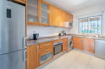 a kitchen with wooden cabinets and a stainless steel refrigerator at Villa Balaia by HelloVacations in Albufeira