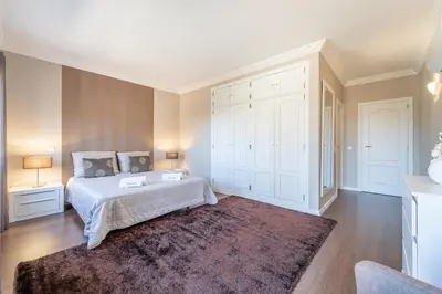 a bedroom with a white bed and a large rug at Villa Balaia by HelloVacations in Albufeira