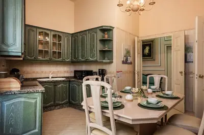 a kitchen with green cabinets and a table with chairs at Casa Beny 1897 Guesthouse in Loulé
