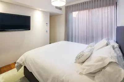 a bedroom with a white bed and a flat screen tv at L Orangerie CA by Intiholidays in Vilamoura