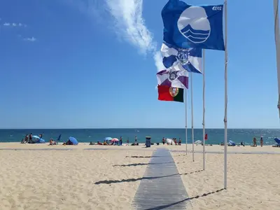 a row of flags on a beach with the ocean at T1 V do Forte AC&Piscina&Garagem in Quarteira