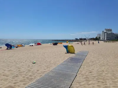 a sandy beach with a wooden walkway and people on the beach at T1 V do Forte AC&Piscina&Garagem in Quarteira